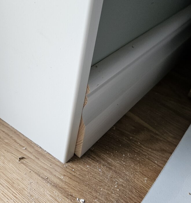 Allmogelist och smyg vid dörrkarm, där listen inte möter smygen snyggt. Träytan och listen syns tydligt, med en ojämn kant.