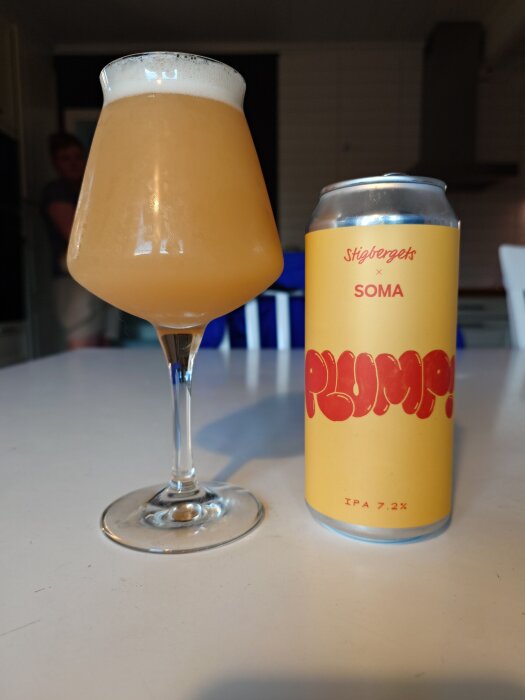 En ölglas och en burk med etiketten "Stigbergets x SOMA Plump! IPA 7.2%" på ett köksbord.