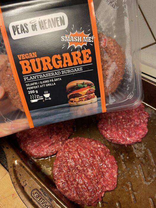 Förpackning med Peas of Heaven's veganska burgare och köttpuckar på plåt, redo för grillning.