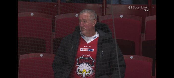 Person i hockeytröja från Malmö Redhawks på en tom läktare.