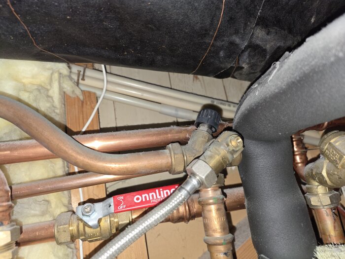 Rörinstallation med kopparrör, isolering, ventiler och varmvattenrör i ett byggprojekt.