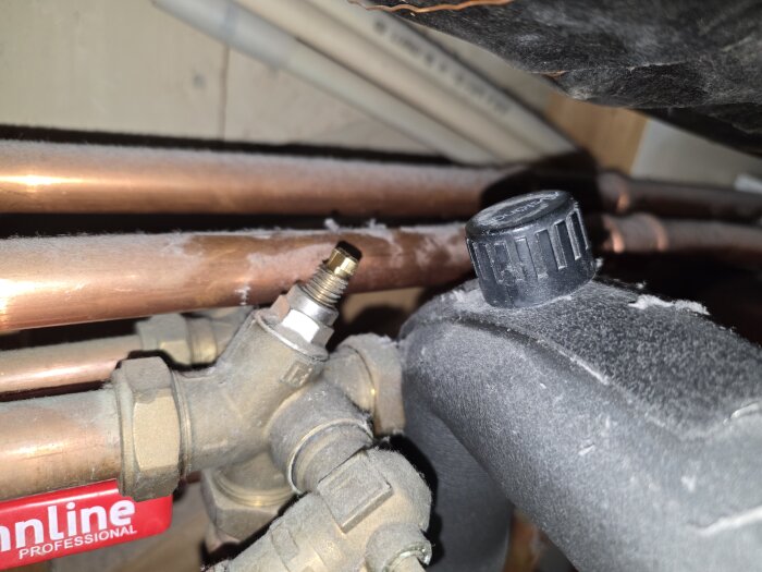 Rörkopplingar av koppar med ventil och plastlock, inomhusmiljö.