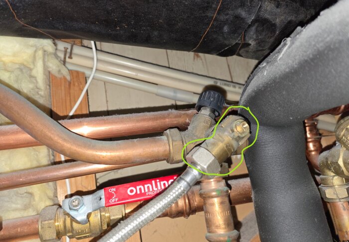 Påfyllningsventil utan vred i ett rörsystem, markerad med grön cirkel och omgiven av kopparrör.