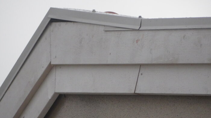 Närbild av en husgavel med vitt takfoder och plåtarbete på takhörnet, som visar monteringsdetaljer och finish.