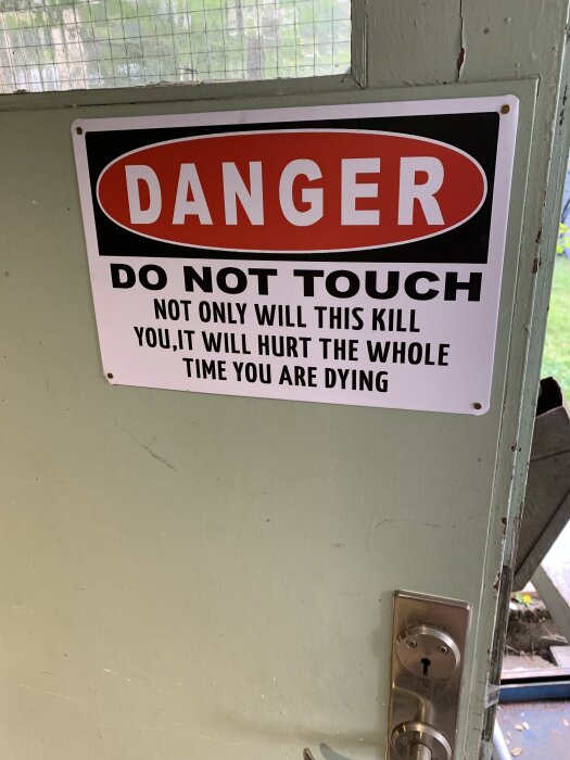En varningsskylt på en trädörr med texten "DANGER, DO NOT TOUCH, NOT ONLY WILL THIS KILL YOU, IT WILL HURT THE WHOLE TIME YOU ARE DYING".