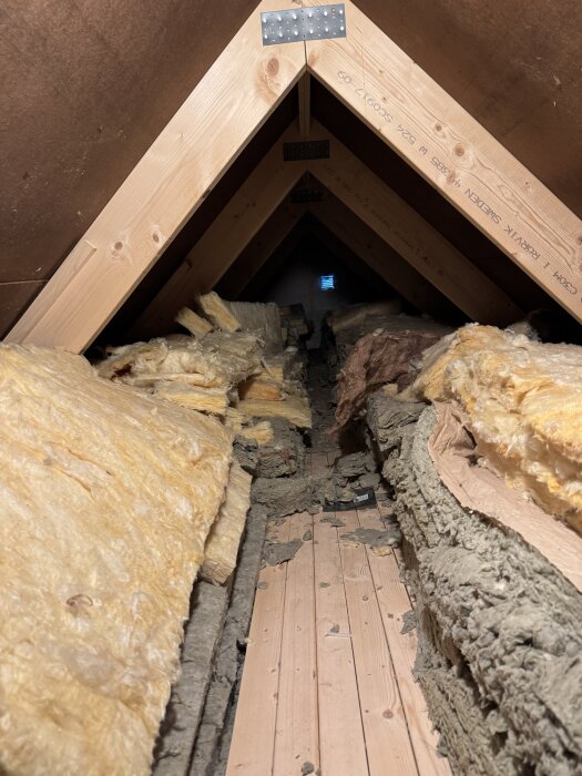 Vind med träbjälkar och delvis lagd isolering, en synlig träbro saknar isolering.