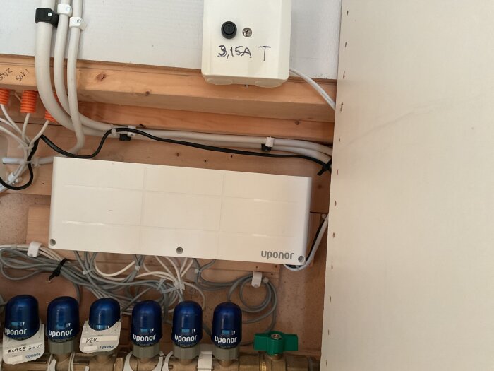 Elinstallation med Uponor-komponenter och en märkning för 3,15 A trög säkring i ett tekniskt skåp, med synliga kablar och rör.