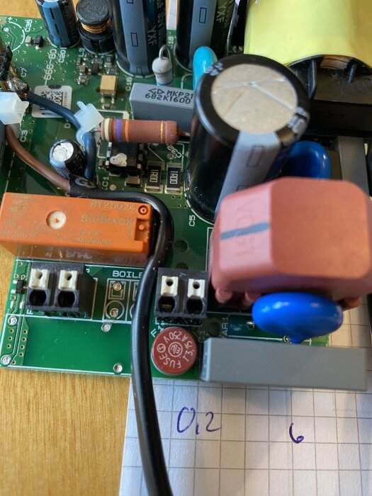 Närbild på ett kretskort med diverse elektroniska komponenter, inklusive en nylödd metalloxidvaristor och en extern säkring på 3,15 A.