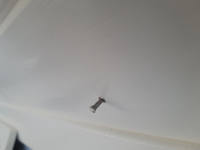 Spik i träpanel i taket som verkar vara på väg att lossna.