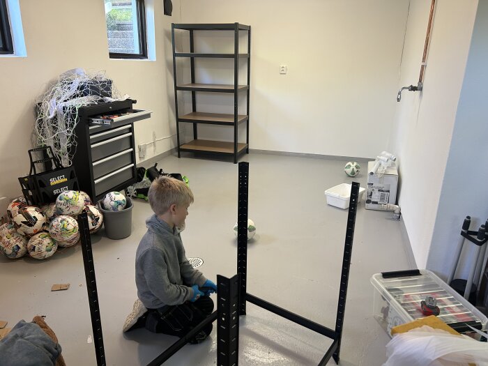 Barn bygger lagerhylla i ett garage. Hyllor, verktygslåda, fotbollar och nät syns i närheten.