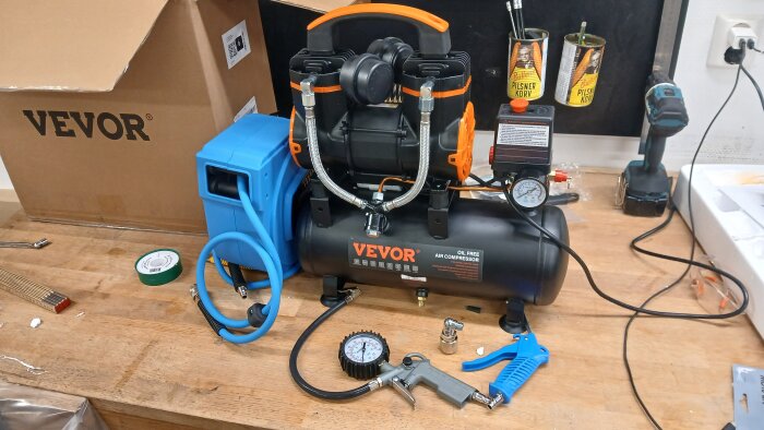 Tryckluftskompressor med tillbehör på en arbetsbänk i garaget.