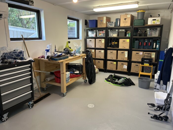 Verkstad med verktygstavla, lådor och arbetsbänk. Ordentlig organisering med förvaringshyllor fyllda med lådor och verktyg.