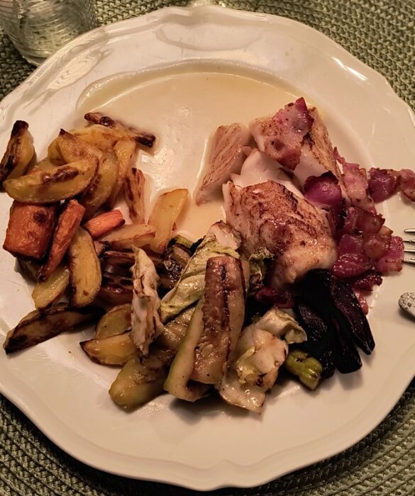 Tallrik med stekt torsk, baconbitar, potatisklyftor, morot, ugnsstekta rödbetor, squash och spetskål. Serverad med en champagne- och chilidressing.