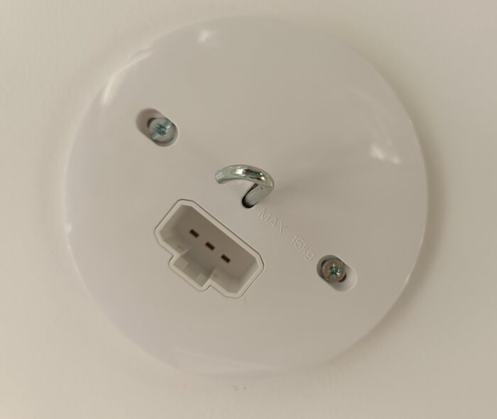 Taklamputtag med krok och två skruvhål syns, maxbelastning 15 kg. Inget uppenbart fäste för armatur i modern uttagsdesign.