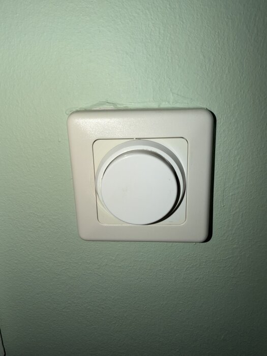 En vit dimmer monterad på en ljusgrön vägg.