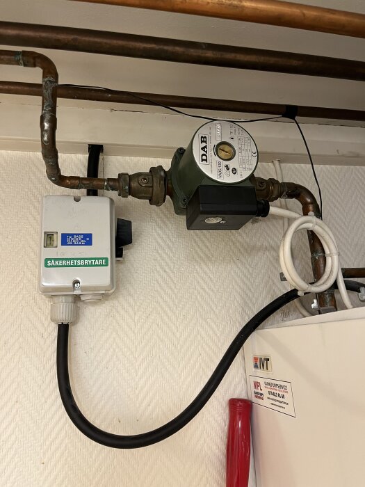 Säkerhetsbrytare och cirkulationspump för värmesystem med kopparrör och vattenledning, märkt "DAB"; används för att stänga av och lufta radiatorer.