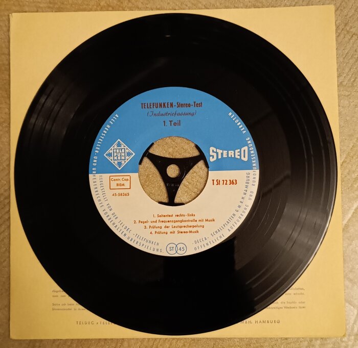 En gammal Telefunken Stereo-Test vinylskiva med blå etikett och tysk text, placerad på ett fodral.