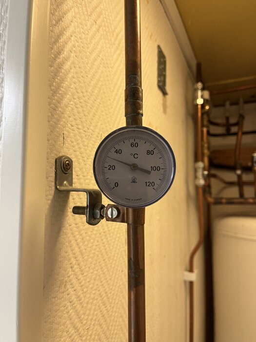 Termometer på kopparrör visar aktuell temperatur i värmesystem, indikation på om temperaturen på 30 grader är lämplig för bergvärmeinstallation.