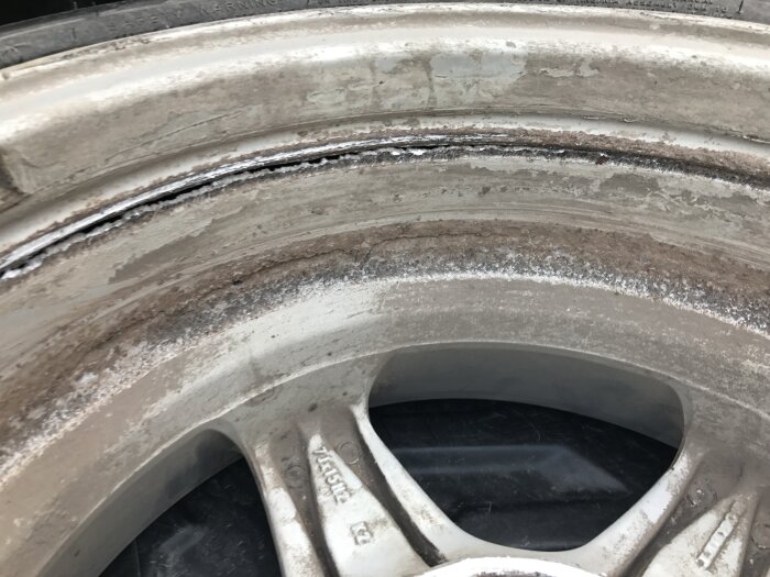 Närbild på en skadad fälg med slitage och rostbildning på insidan.