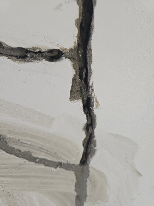 Sprickor i en källarvägg lagade med ankarmassa och lagningsbruk, nära fotograferade för att visa reparationsprocessens detaljer.