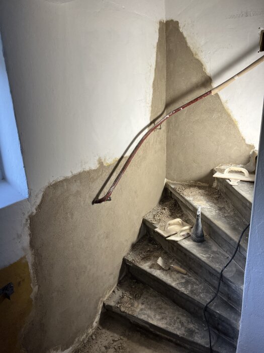Renovering av trappa med bortbilad gammal lagning och nya kalkbruk, verktyg synliga på stegen.