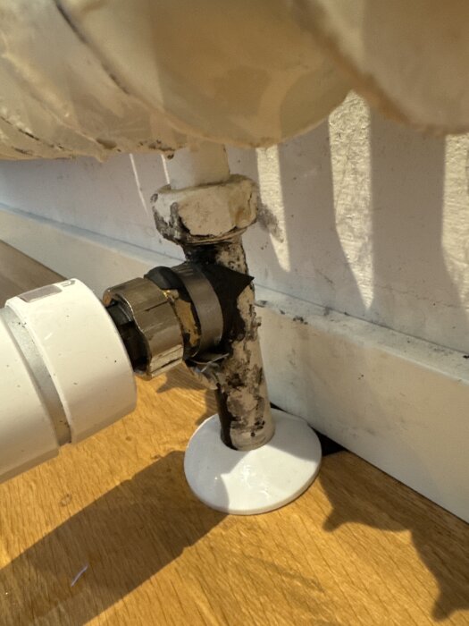 Närbild på ett rör med självvulkaniserande tejp vid basen, ansluten till ett element mot en vägg. Tejpen täcker en vattenläcka i röret.