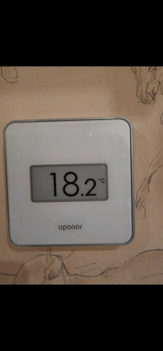 Rumsgivare på vägg visar 18,2 grader Celsius, märkt Uponor.