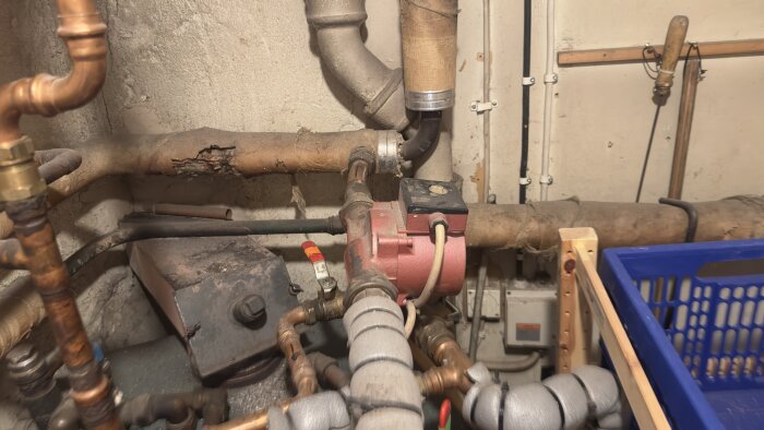 Pannrum med vattenrör, kulventiler och en cirkulationspump i ett vattenburet värmesystem.