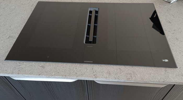 Siemens häll med inbyggd fläkt från Studio line IQ 700-serien, monterad på grå köksbänk.