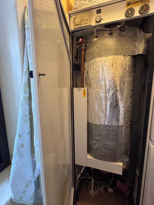 Gammal elpanna Euronom C15EK från 1983 i en tvättstuga med avskalad isolering och synliga rör och kablar.