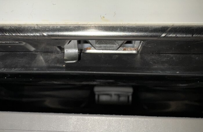 Närbild av en metallkrok och en triangulär komponent som justerats med en skruvmejsel.