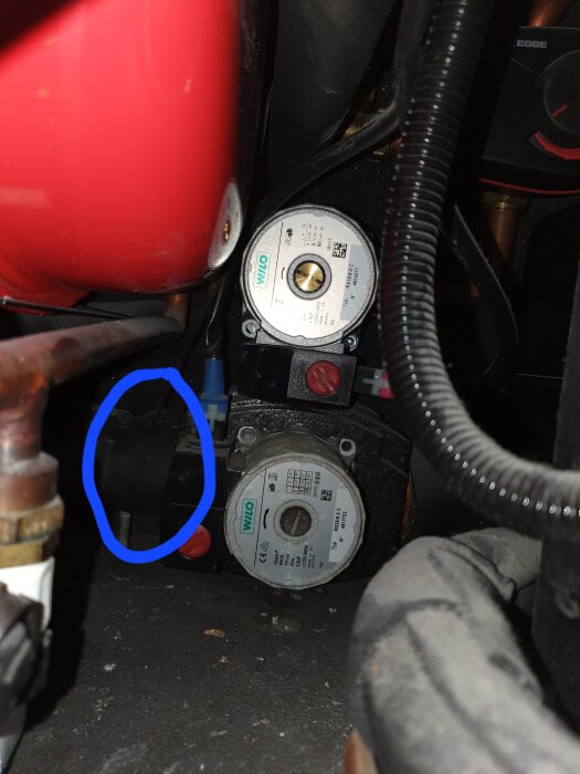 En Wilo-cirkulationspump med en blå inringad komponent, potentiellt en köldbärargivare, visas i ett värmepumpsystem.