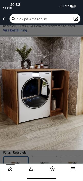 En vit tvättmaskin i ett skåp av ek med skåp och hyllor, dekorerad med växter och flaskor mot en marmorliknande bakgrund.