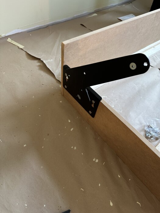 Byggfas av sängskåp med synligt beslag monterat på sängram av MDF; visar konstruktionens detalj i ett rum under renovering.