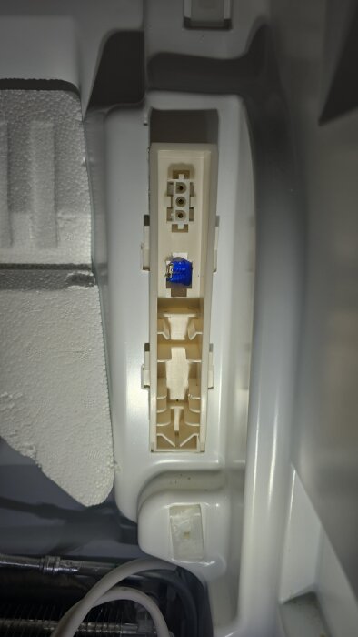 Bilden visar en inre del av en Electrolux EUE9000X-kontakt med en blå komponent och anslutningar i plastkapsling.