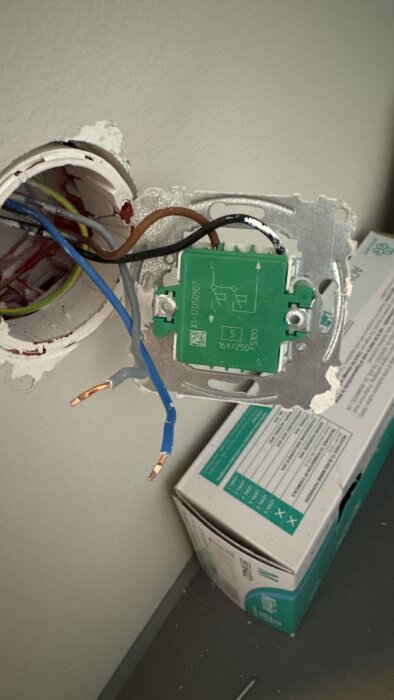 Eluttag med urdragna kablar och en plejd-puck i fokus, kablarna hänger löst från väggen.