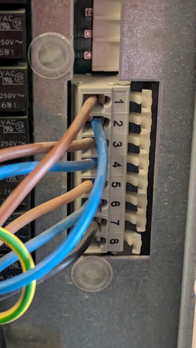 Kabelanslutningar i en Nibe Fighter 1215 värmepump med numrerade terminaler och färgade kablar.