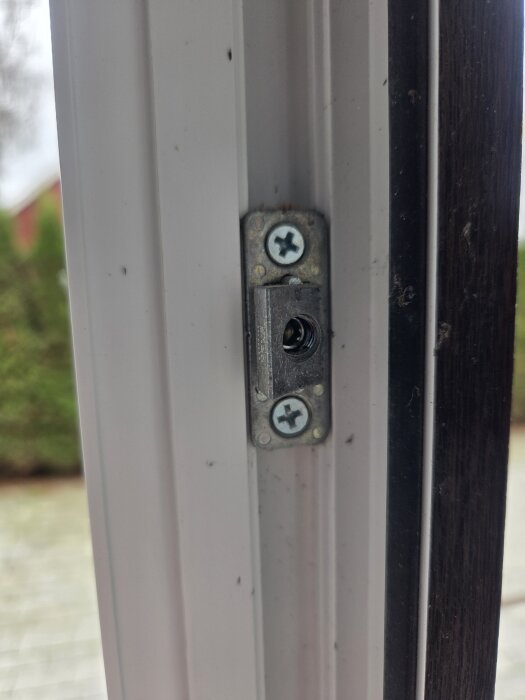 Närbild på metallskruvar i ett gångjärn på sidan av ett PVC-fönster, visar en justeringsmöjlighet via två skruvar.