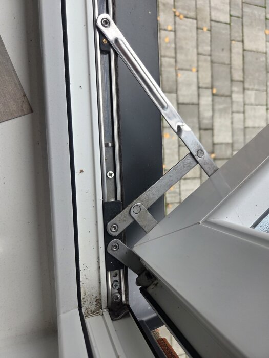 Närbild på öppet PVC-fönster med gångjärn vid kanten, visar lucka i hörnet på grund av gångjärnsproblem.