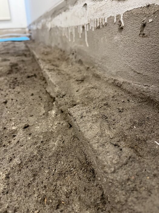 Ojämnt golv i källare med betongvägg och spår av murbruk, med diskussion om regler och golvläggning.