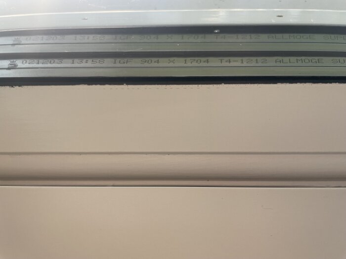 Fönsterprofil med stämplad kod och liten kronliknande symbol; okänd fönstertillverkare efter kontroll med Kronfönster.