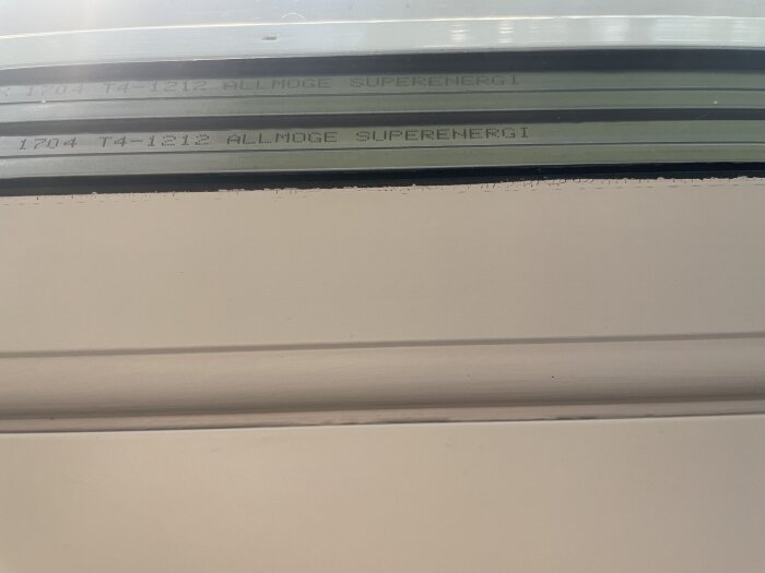 Fönsterkarm med texten "1704 T4-1212 ALLMOGE SUPERENERGI", användare söker information om tillverkaren.