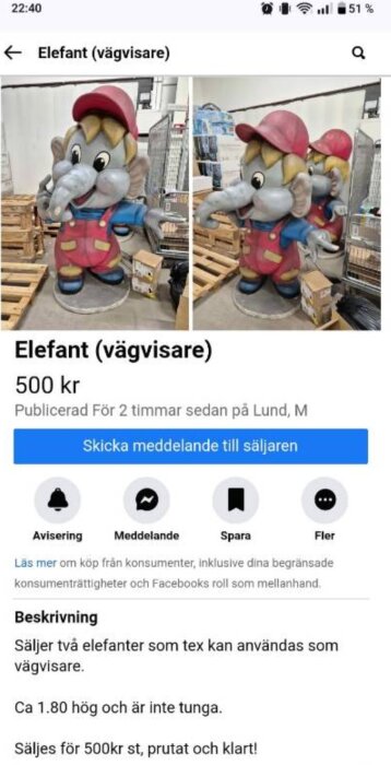 Två figurer av elefanter i kläder med keps, används som vägvisare. Står på golv med trälådor och andra föremål i bakgrunden. Pris 500 kr styck.