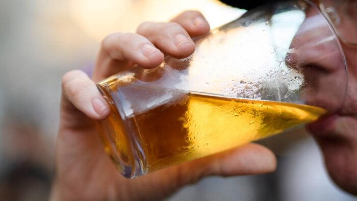 Person dricker ett glas öl.