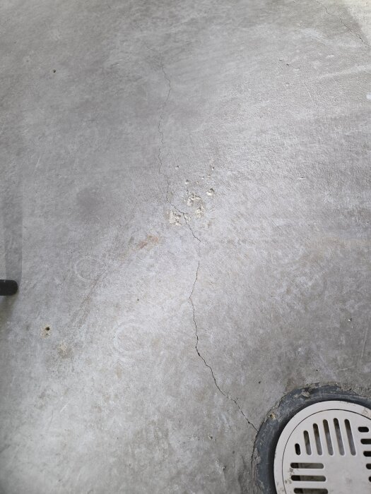 Spricka i betonggolv med närhet till golvbrunn i källare.