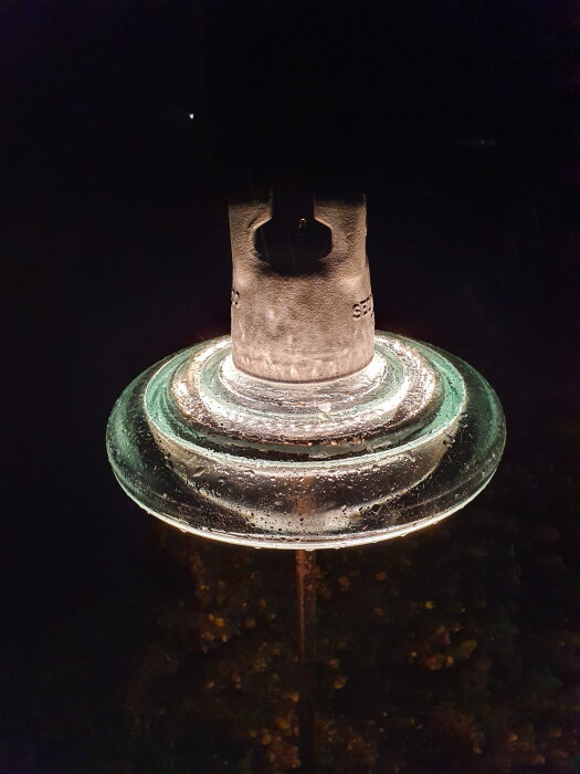 Isolator omvandlad till trädgårdsbelysning med ljus som lyser upp en glaskupa mot en mörk bakgrund.