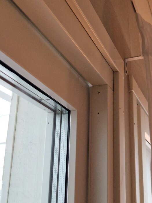 Innerdel av vit altandörr som glipar i övre hörnet och tycks vara svår att stänga ordentligt, potentiellt på grund av justeringsproblem.