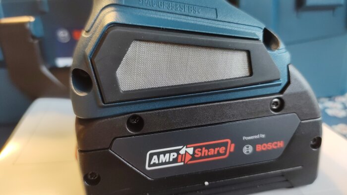 Närbild på en Bosch batteripack med AMPShare-logotyp och texten "Powered by Bosch", placerad mot en suddig bakgrund.