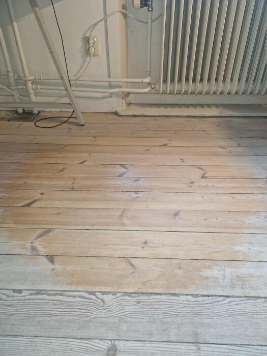 Trägolv med synligt slitage och skrapmärken nära element.