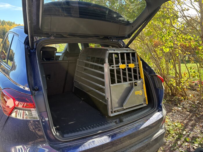En hundbur placerad i bagageutrymmet på en Audi Q4 e-tron med öppet baklucka, visande att den inte riktigt får plats.